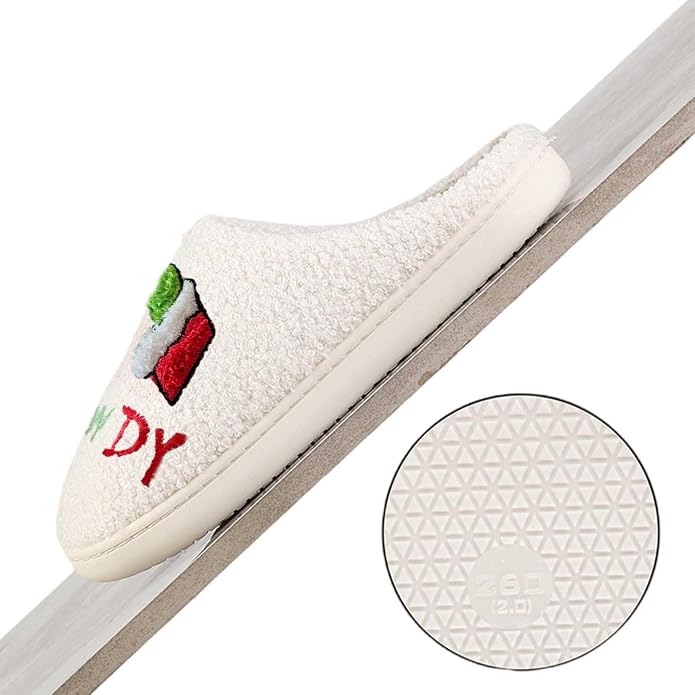 Cream-colored fuzzy slipper with a 3D embroidered Christmas design in red and green, shown at an angle. A circular inset shows the textured rubber sole with a geometric triangle pattern.