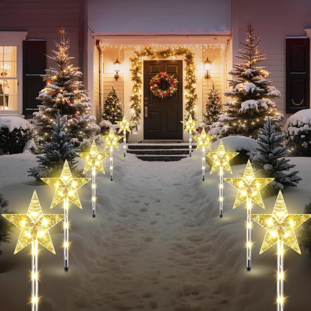 Warm white star solar Christmas pathway stake lights lining both sides of snowy walkway at night