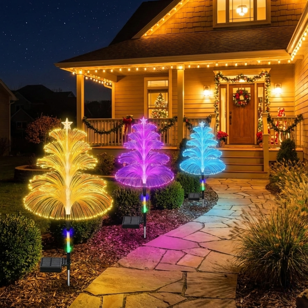 Three solar RGB fiber optic Christmas tree pathway lights glowing in warm gold, purple, and blue against a decorated house facade at night