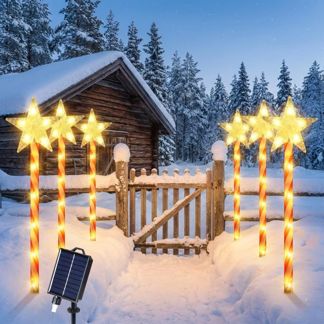 Six solar star candy cane pathway lights with warm white LED stars and red-striped poles staked in snow beside a wooden gate, solar panel in foreground