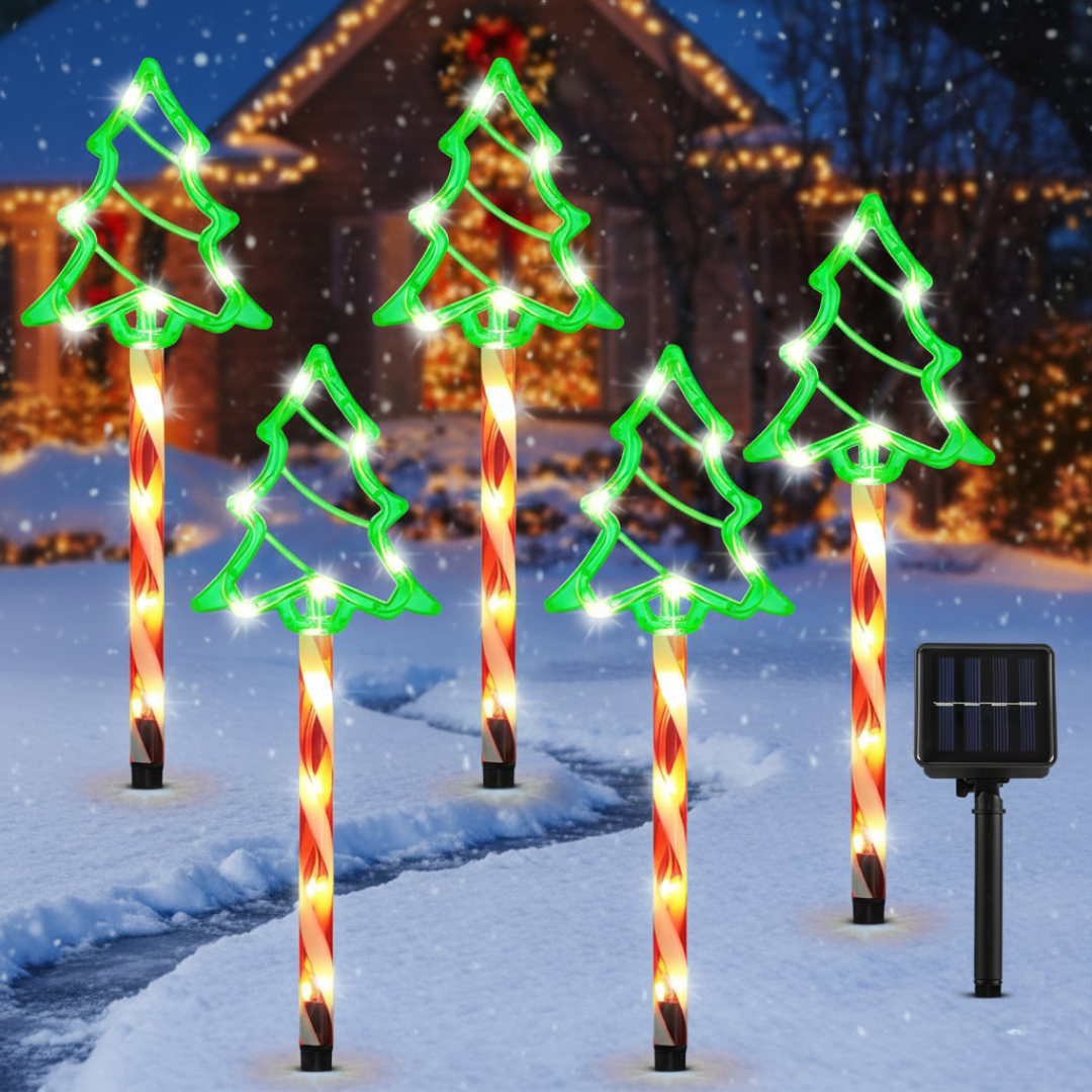 Solar Christmas tree outline pathway lights glowing green with candy-cane striped stakes and snowflakes falling, solar panel beside them