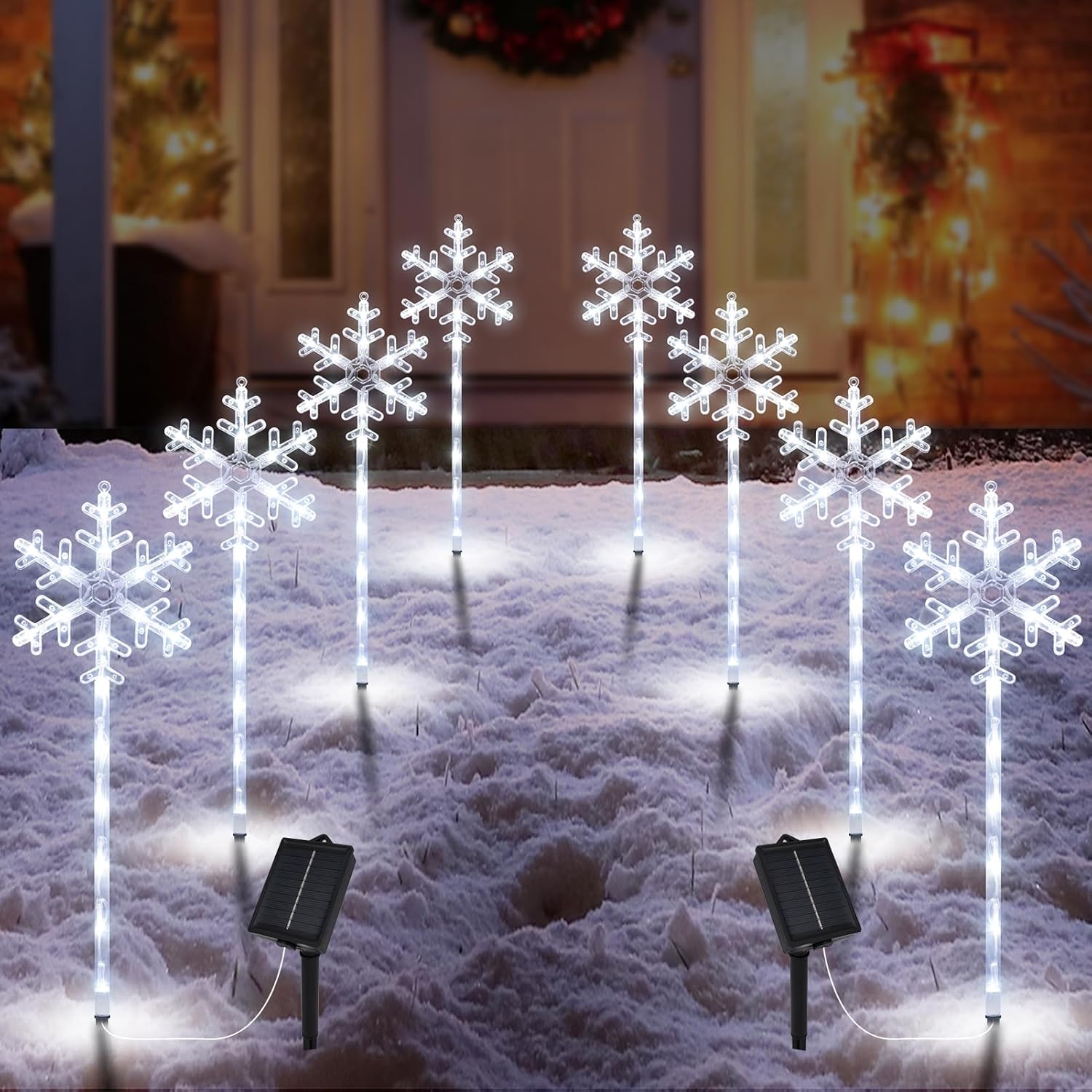 Pack of 8 solar snowflake path lights staked in snow beside a house entrance, warm and cool LED glow at dusk