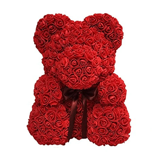 A teddy bear made entirely of red artificial roses with a dark red ribbon tied in a bow around its neck.