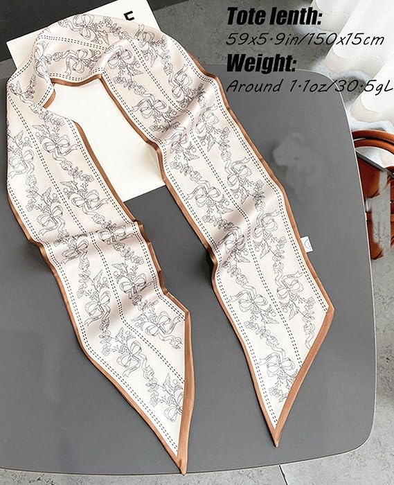 Long narrow satin scarf in cream with a tan border, displayed flat on a gray surface. Features a repeating bow and floral print in gray. Text overlay reads: Tote length: 59x5.9in/150x15cm, Weight: Around 1.1oz/30.5g
