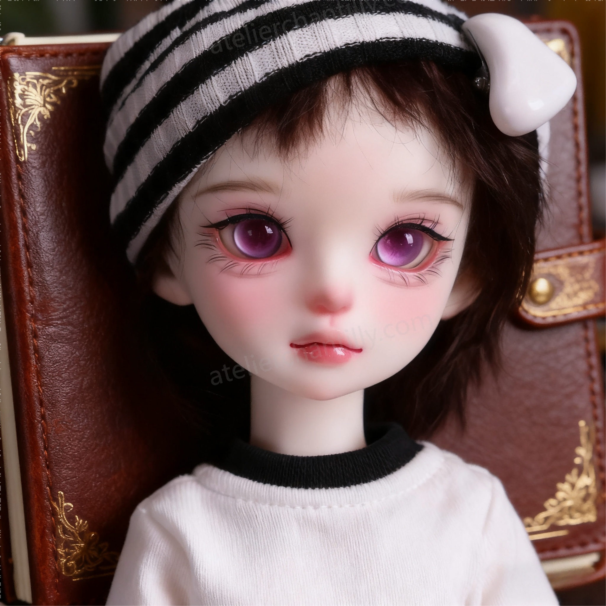Purple glass BJD eyes for 1/4 dolls resting on a vintage leather notebook - Atelier Chantilly