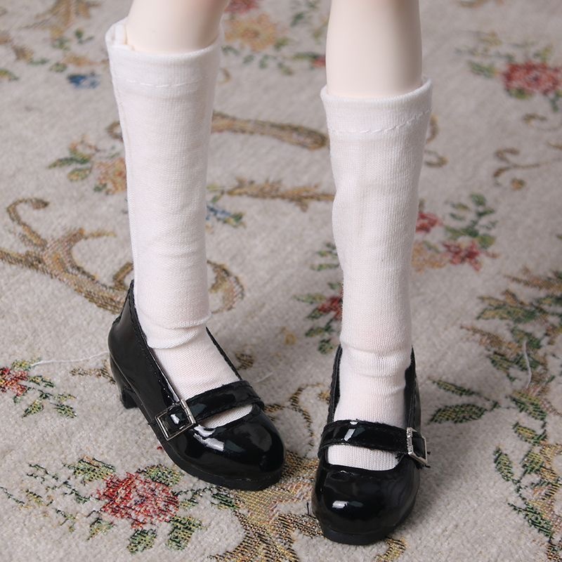 Close-up of black patent BJD Mary Jane shoes and white knee socks