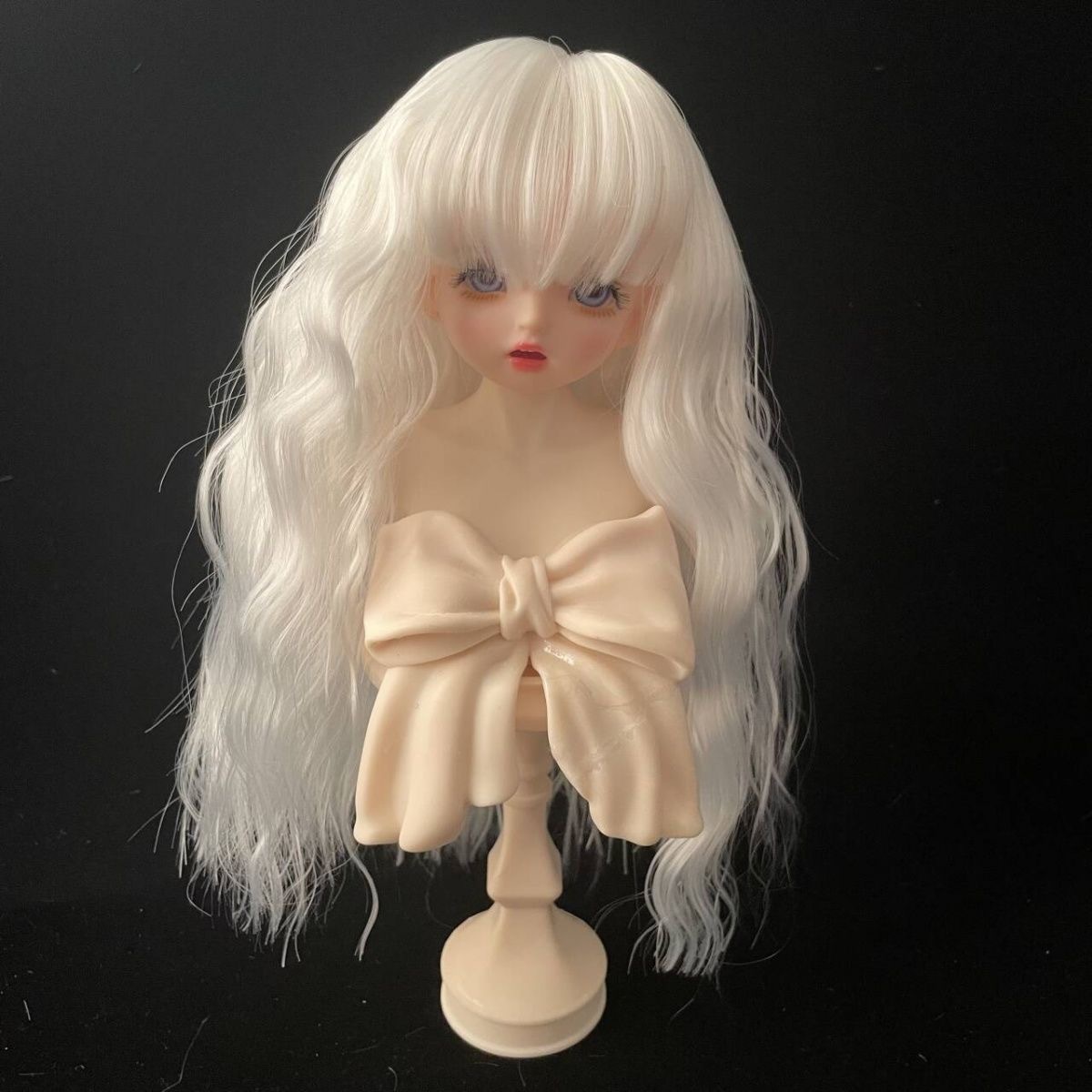 Hand holding long white wig for BJD doll – soft and shiny texture