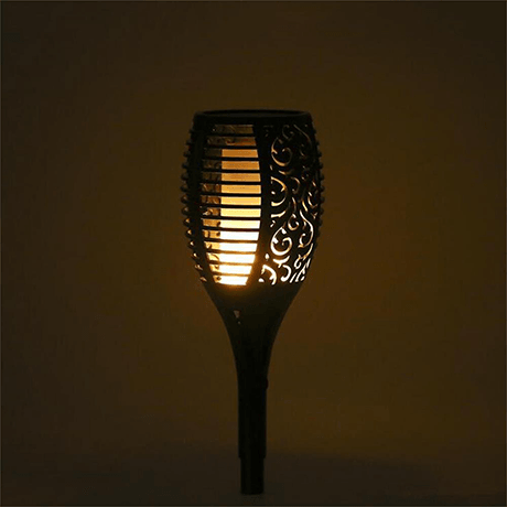 Solar flame flickering torch glowing with warm amber LED flame effect at night