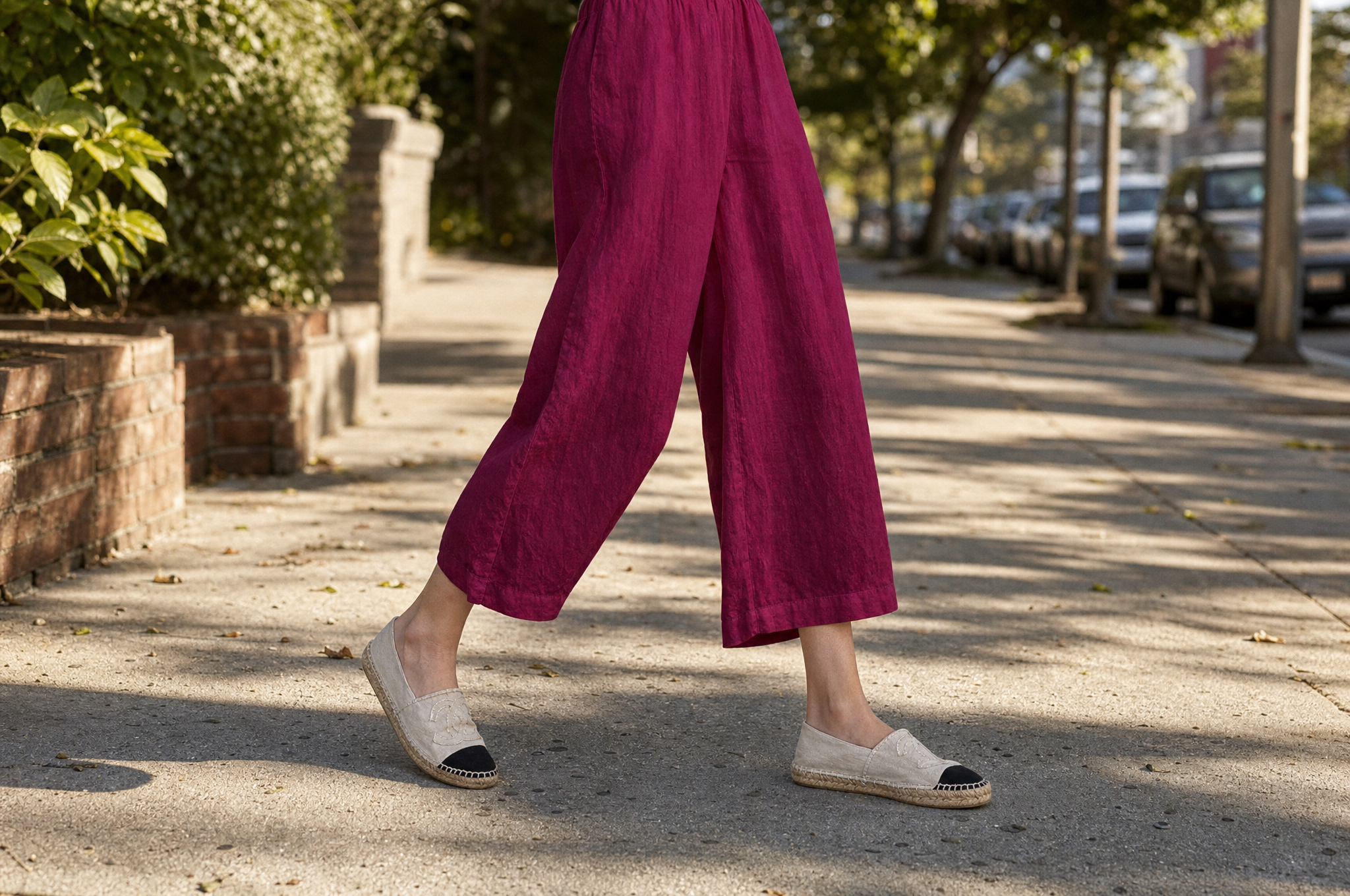 Woman walking on a sunny sidewalk in berry red loose cotton wide-leg capris with canvas espadrilles