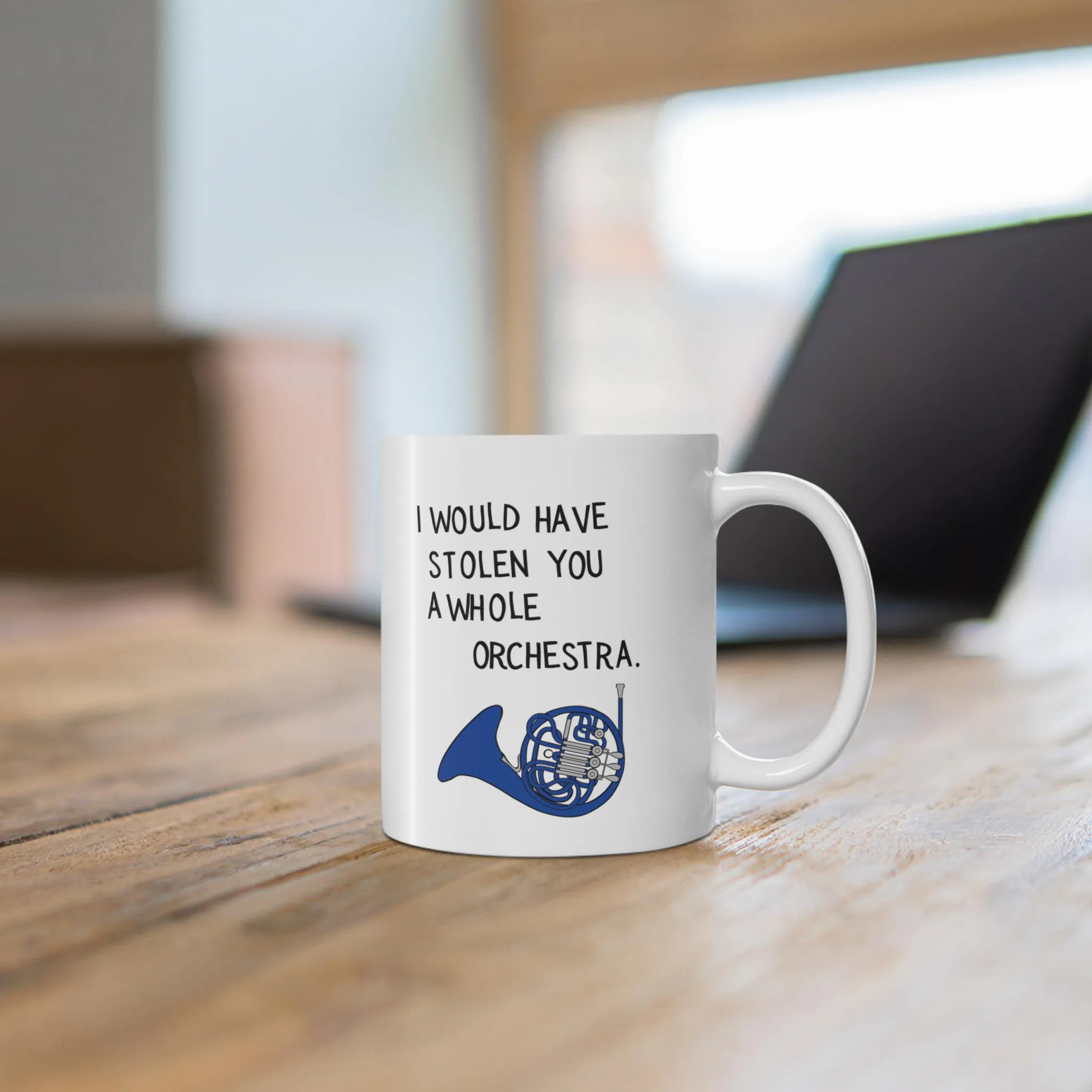 White ceramic mug featuring a blue french horn and the text I Would Have Stolen You A Whole Orchestra on a wooden table