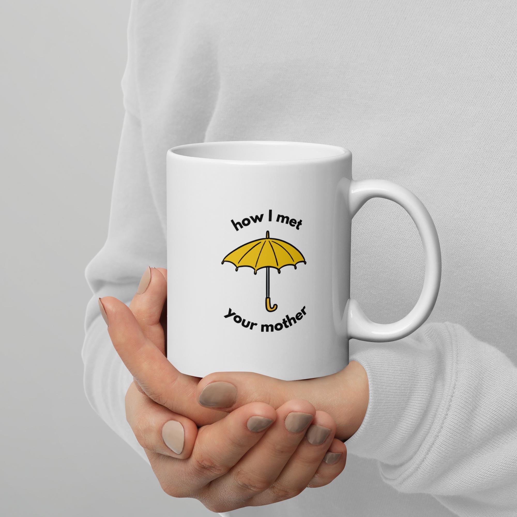 White ceramic mug featuring the yellow umbrella from How I Met Your Mother being held in two hands