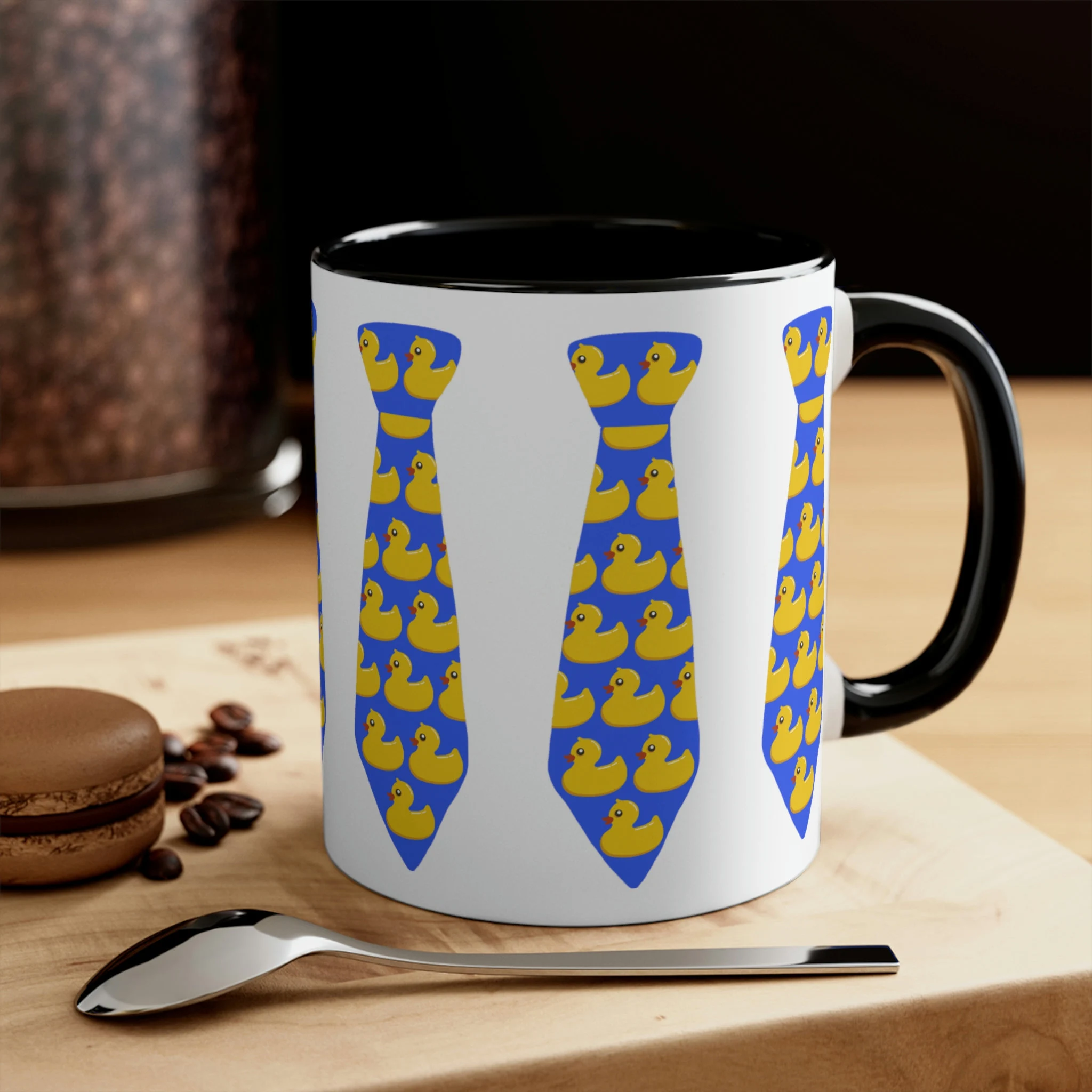 White ceramic mug with black handle and interior featuring yellow rubber ducky necktie print design