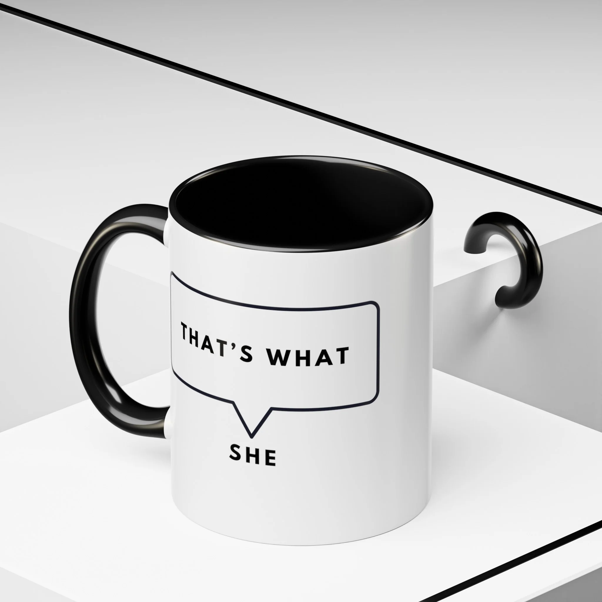 Angled view of white and black ceramic coffee mug on a white geometric background showcaseing the speech bubble design