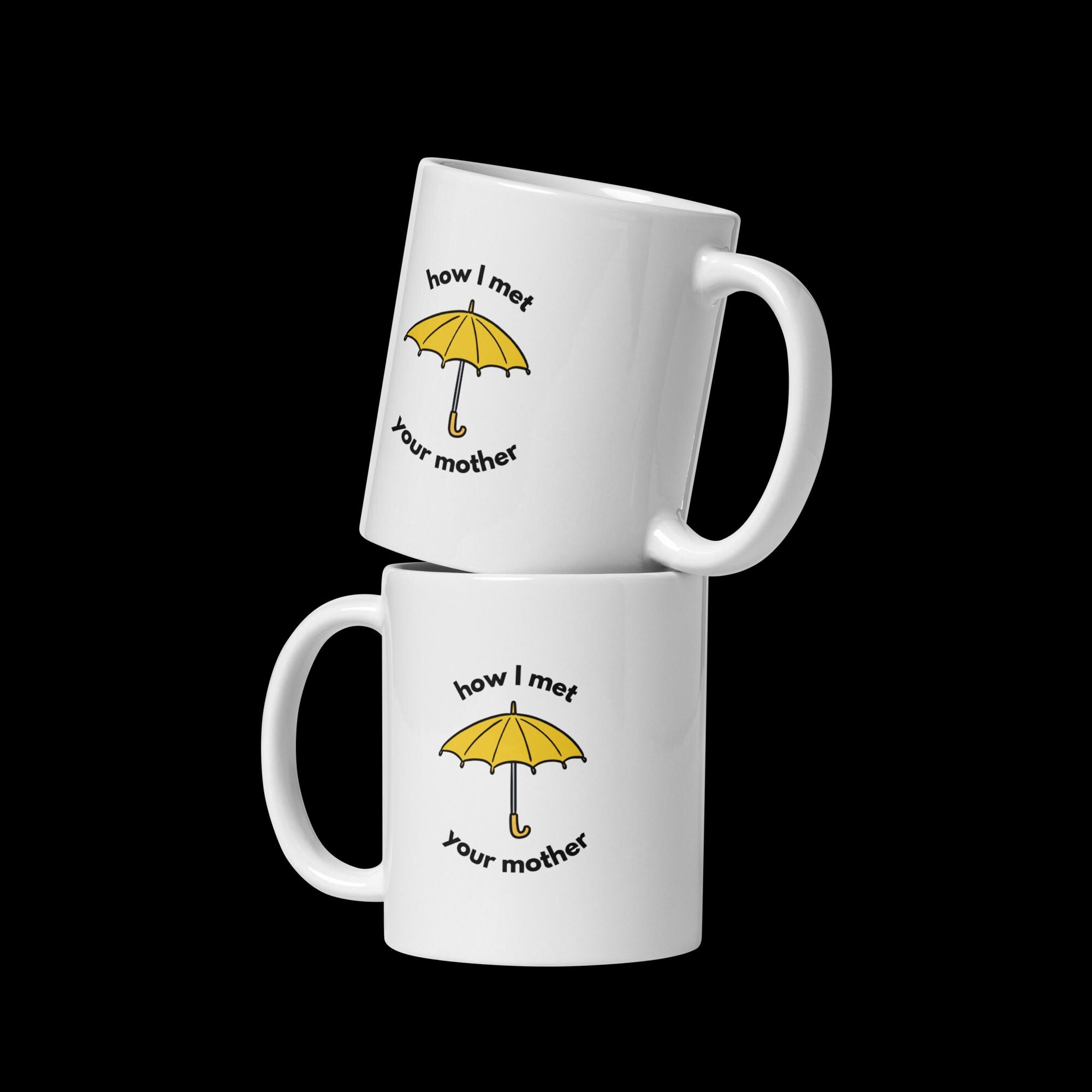 Two stacked white ceramic mugs displaying the How I Met Your Mother yellow umbrella design on a black background
