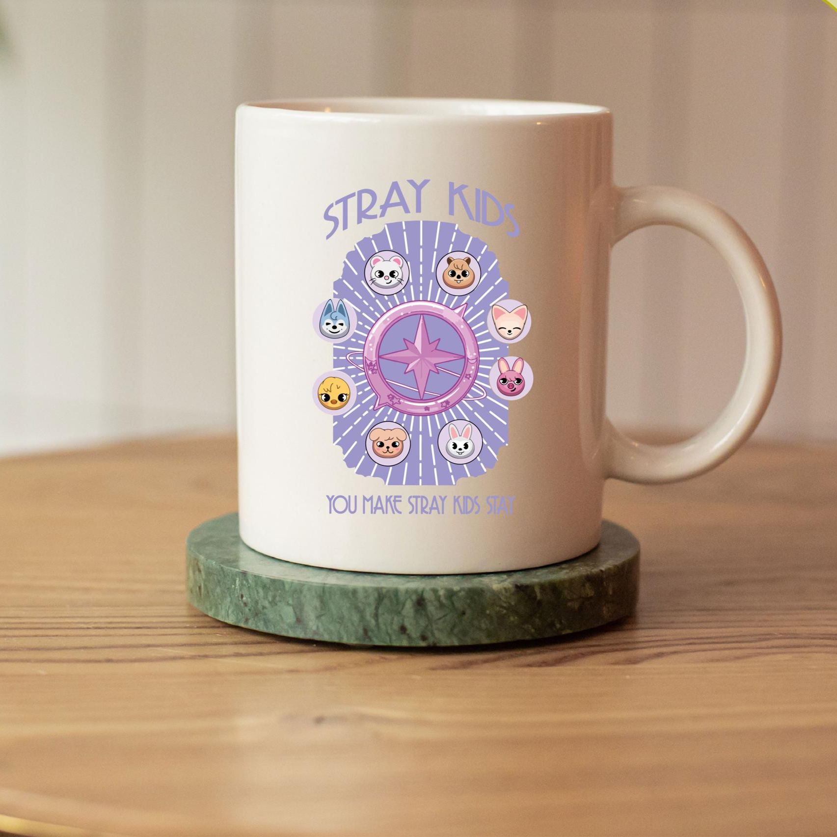 Person holding white ceramic mug with purple Stray Kids Skzoo cartoon characters and compass graphic
