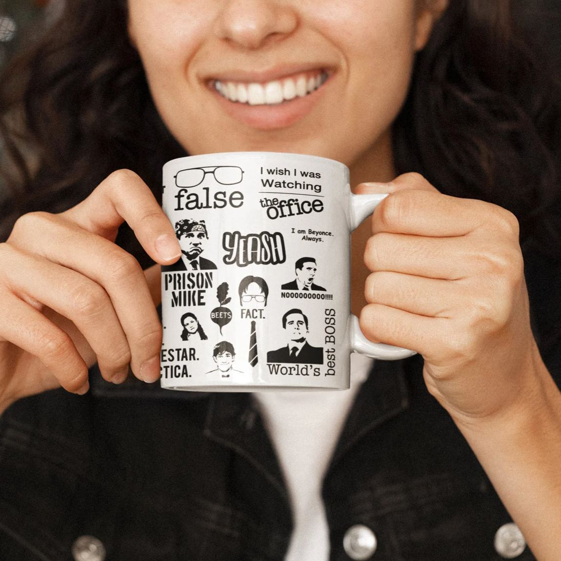 Woman smiling while holding an 11 ounce ceramic mug covered in The Office show references and character art