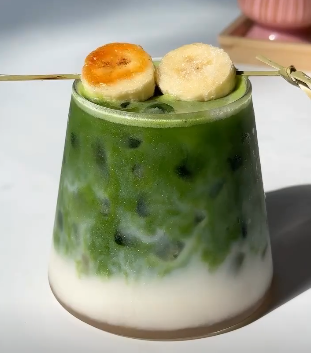 A refreshing glass of green matcha smoothie with banana and spinach.