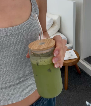 A fashionable American woman taking a break from work to enjoy an iced matcha latte at her desk.