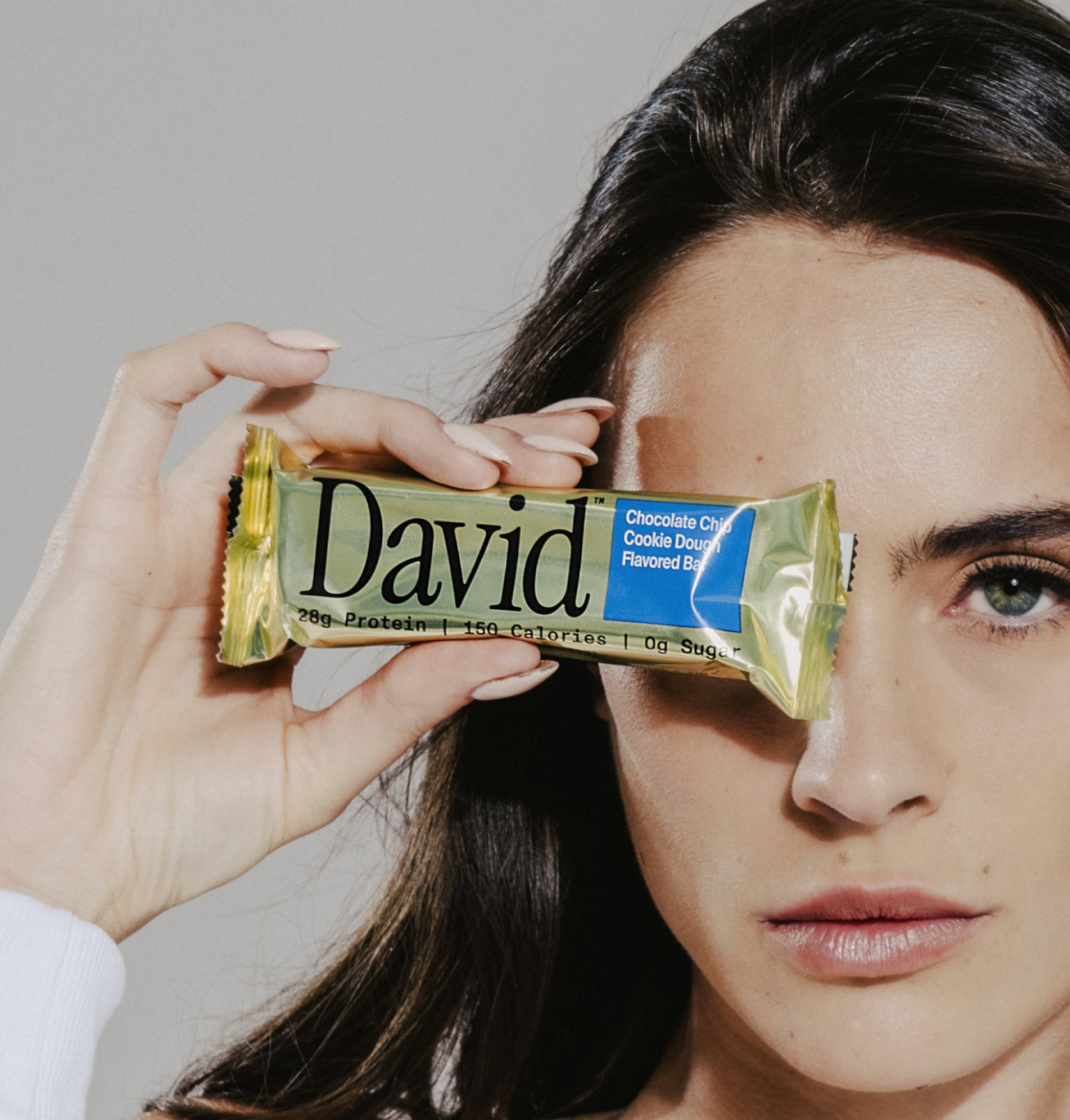 woman holding protein bar at right eye level
