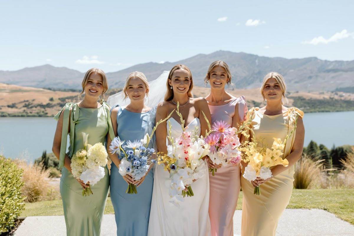 Bride posing with four bridesmaids in different colorful bridesmaid dresses
