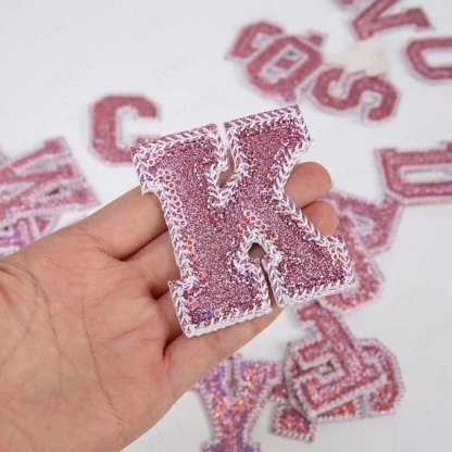 A hand holding a Pink Sequin Iron On Letters.