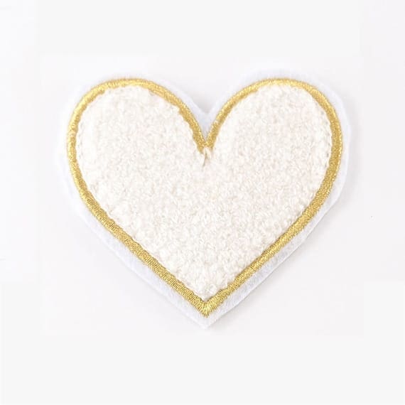 A white and gold heart shaped patch on a white surface.