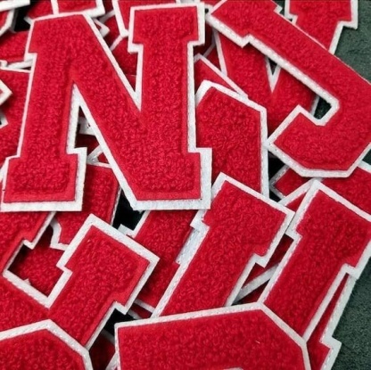 A pile of red chenille iron on letters.