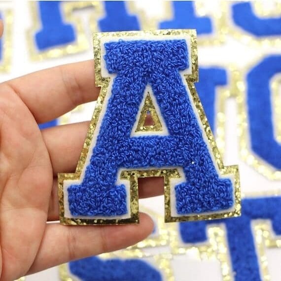 A person is holding a Dazzling Blue Chenille Iron On Letters