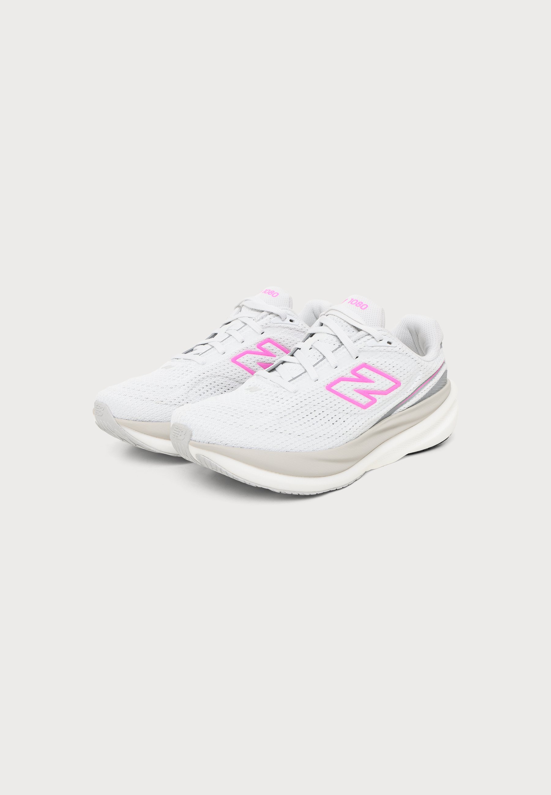 Par de zapatillas deportivas blancas con logotipos "N" en rosa y suelas acolchadas sobre un fondo gris claro.
