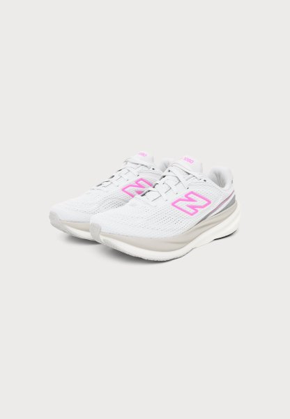 Par de zapatillas deportivas blancas con logotipos "N" en rosa y suelas acolchadas sobre un fondo gris claro.