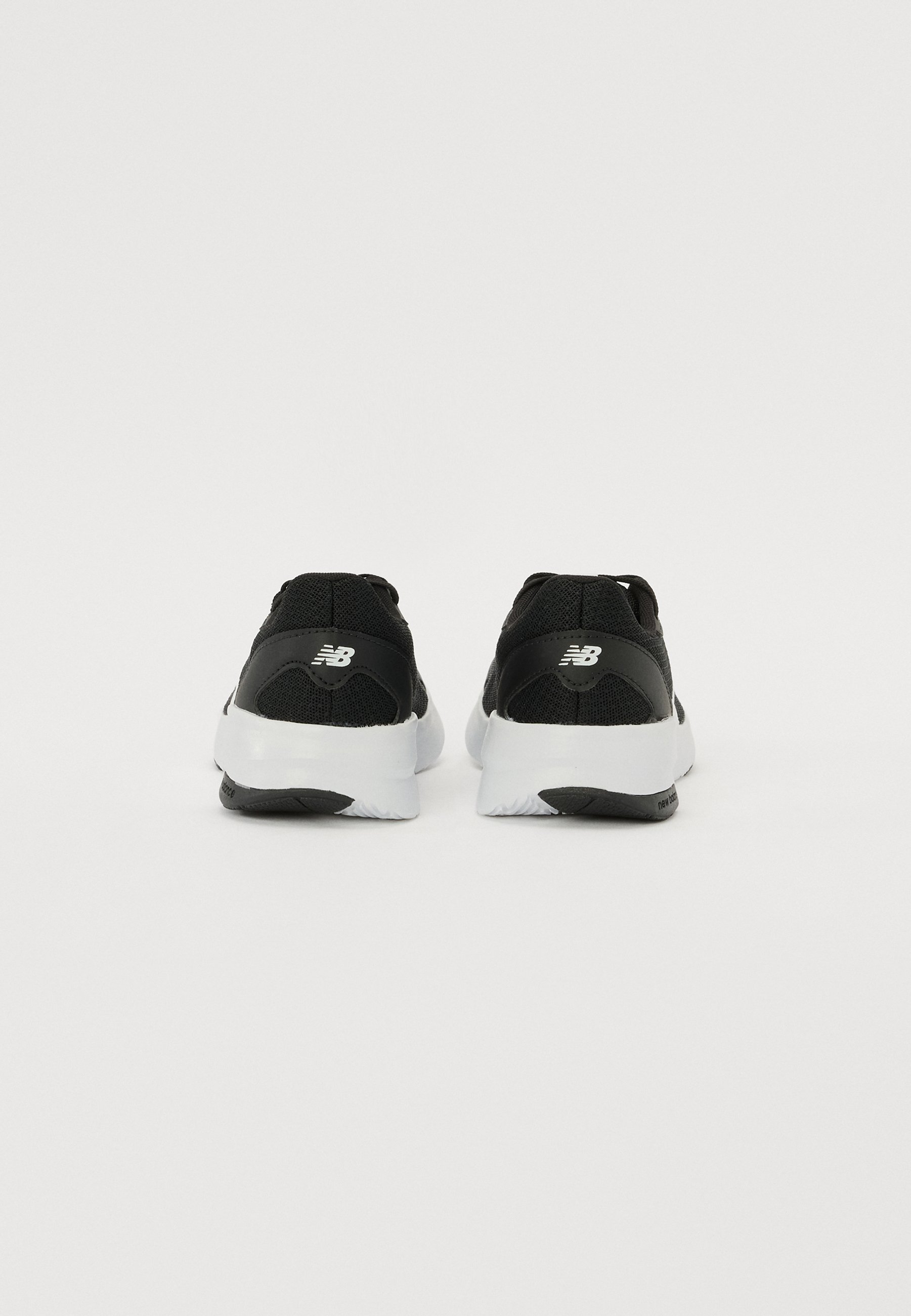 Zapatillas deportivas negras con parte superior de malla, suelas de goma blancas y un logotipo distintivo en el talón, con un diseño texturizado.
