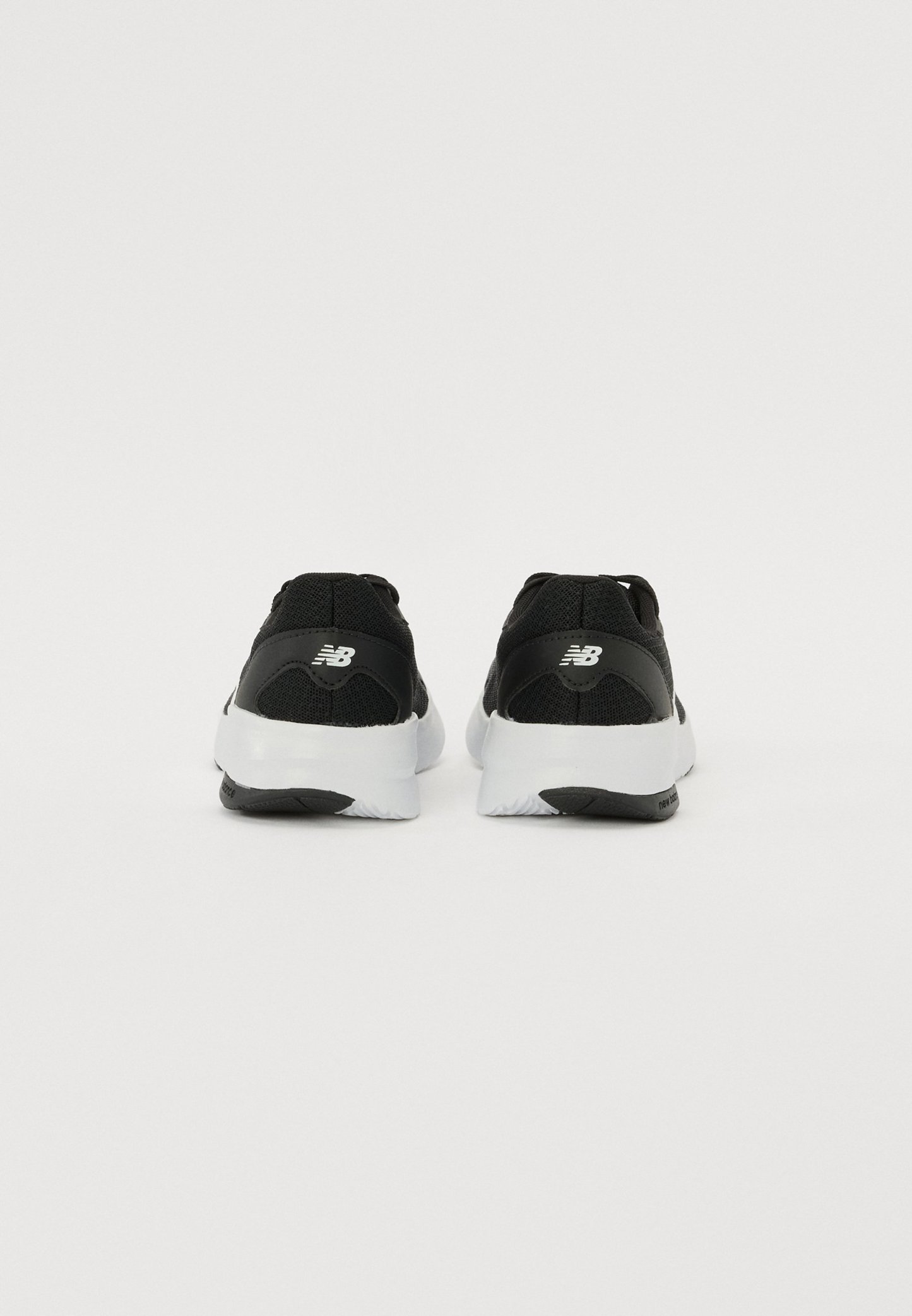 Zapatillas deportivas negras con parte superior de malla, suelas de goma blancas y un logotipo distintivo en el talón, con un diseño texturizado.