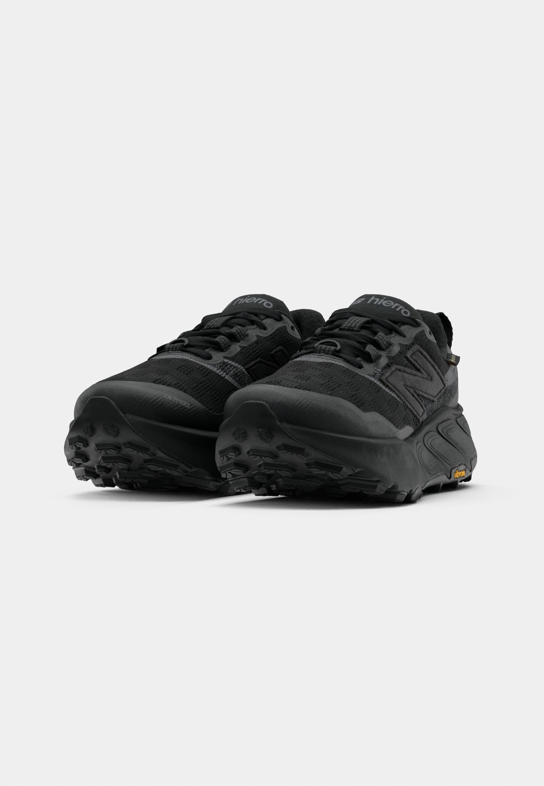 Las zapatillas de trail running negras cuentan con una parte superior de malla con acentos de textil, suelas gruesas y patrones de taco agresivos para una mejor tracción.