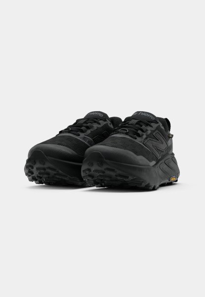 Las zapatillas de trail running negras cuentan con una parte superior de malla con acentos de textil, suelas gruesas y patrones de taco agresivos para una mejor tracción.