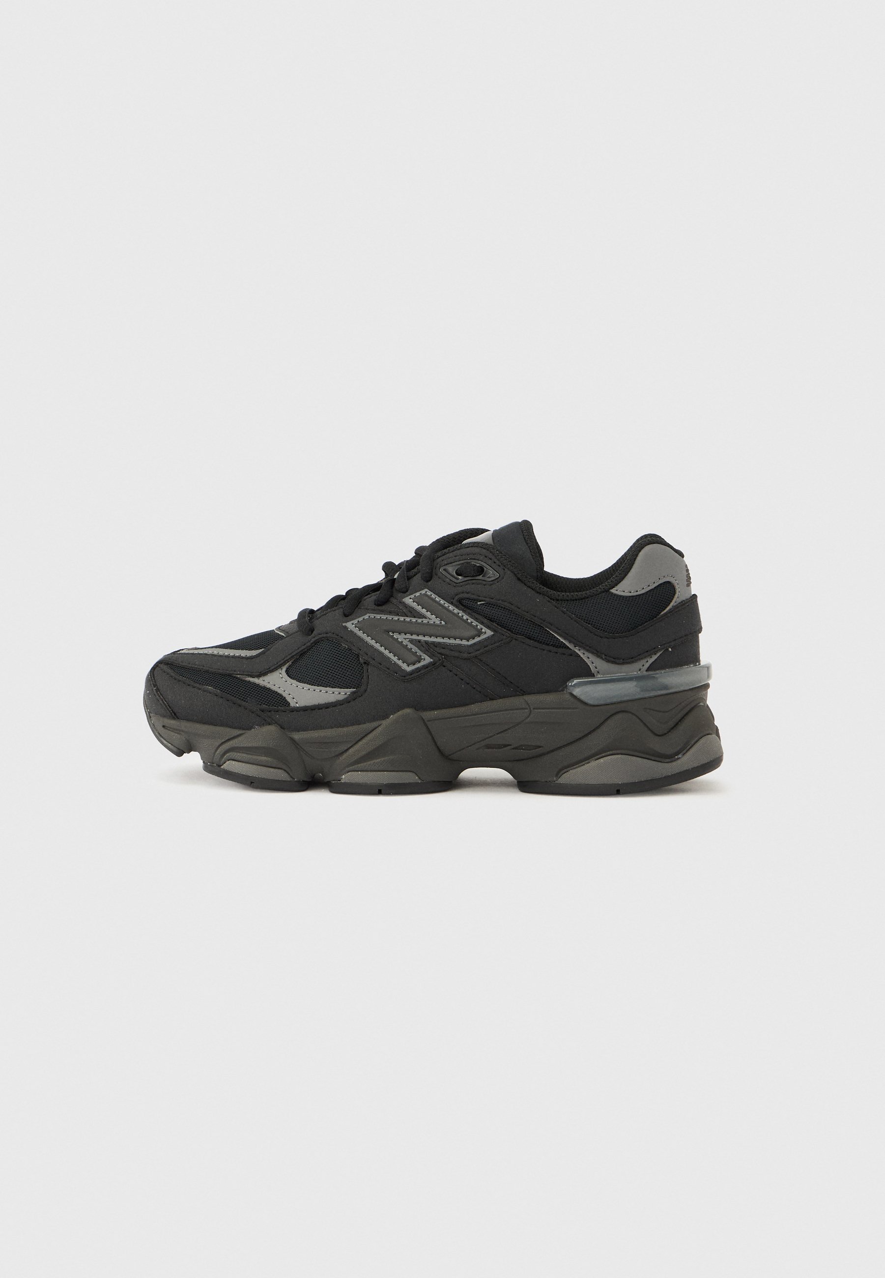 Zapatillas deportivas en negro y gris con una parte superior de tela texturizada, cordones y una suela de goma gruesa con un diseño distintivo y detalles.