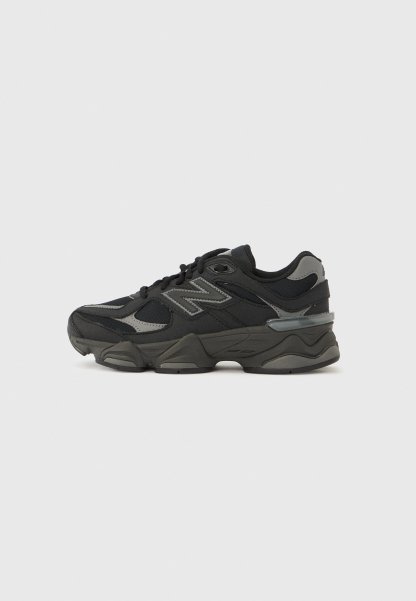 Zapatillas deportivas en negro y gris con una parte superior de tela texturizada, cordones y una suela de goma gruesa con un diseño distintivo y detalles.