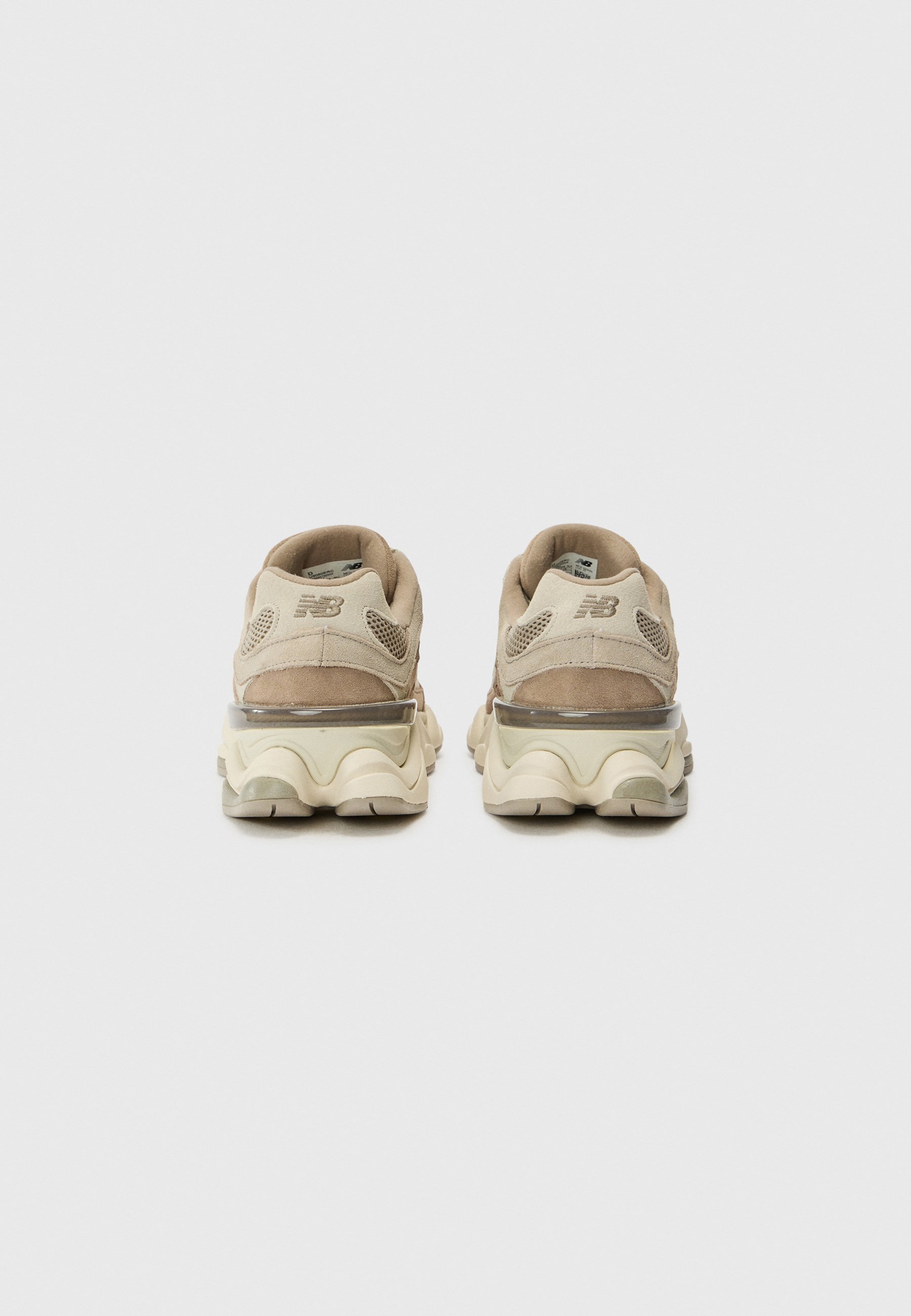 Zapatillas deportivas de color beige claro con parte superior de ante y malla, acentos texturizados y una suela gruesa y acolchada con amortiguación de aire visible.
