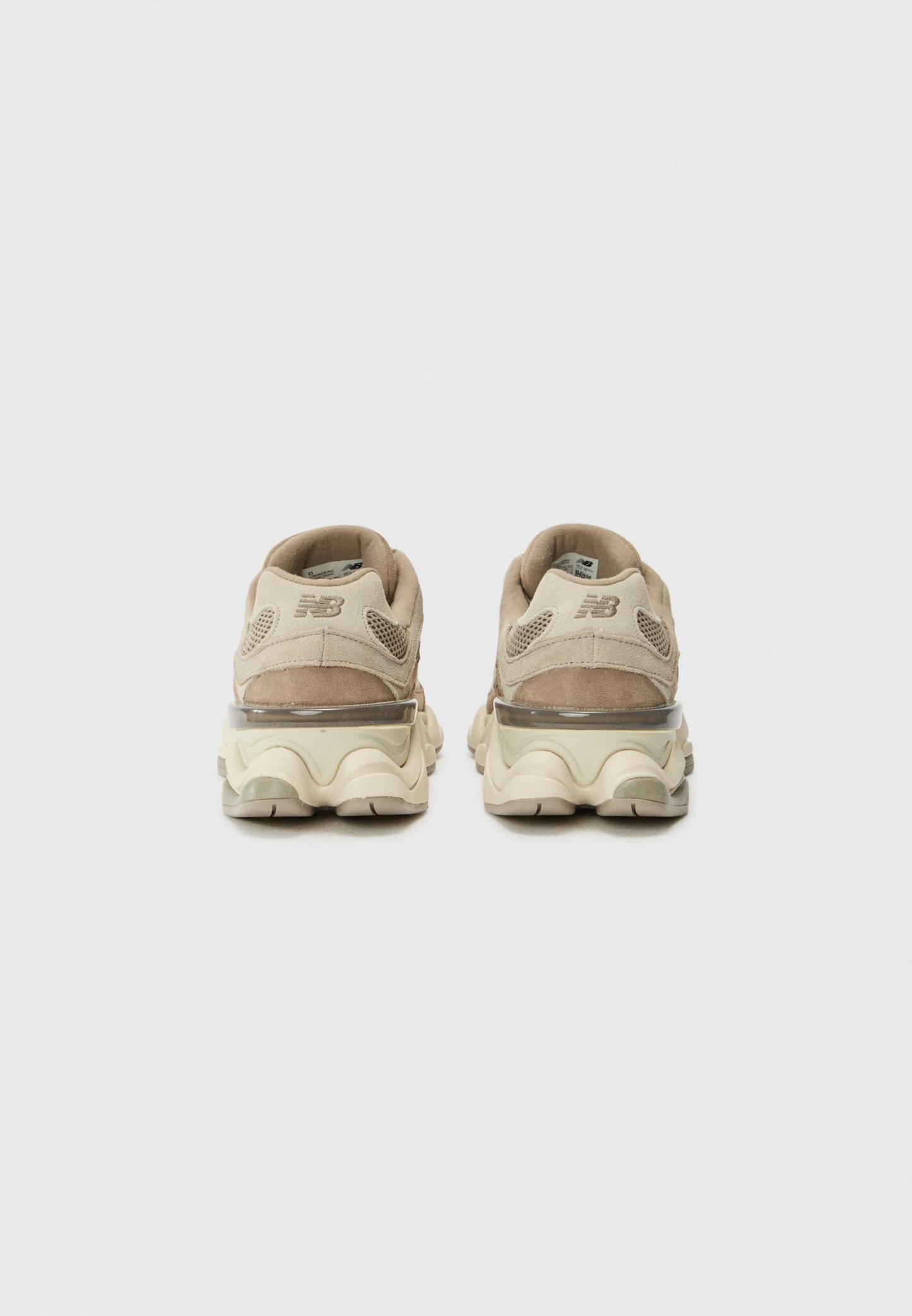 Zapatillas deportivas de color beige claro con parte superior de ante y malla, acentos texturizados y una suela gruesa y acolchada con amortiguación de aire visible.