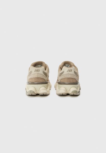 Zapatillas deportivas de color beige claro con parte superior de ante y malla, acentos texturizados y una suela gruesa y acolchada con amortiguación de aire visible.