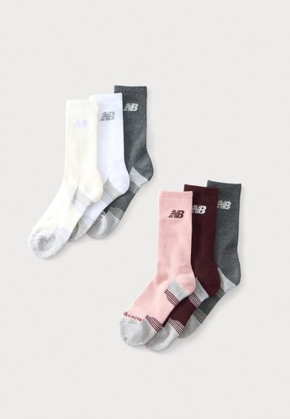 Tres pares de calcetines New Balance crew en blanco, gris, rosa, burdeos y gris oscuro dispuestos sobre un fondo claro.