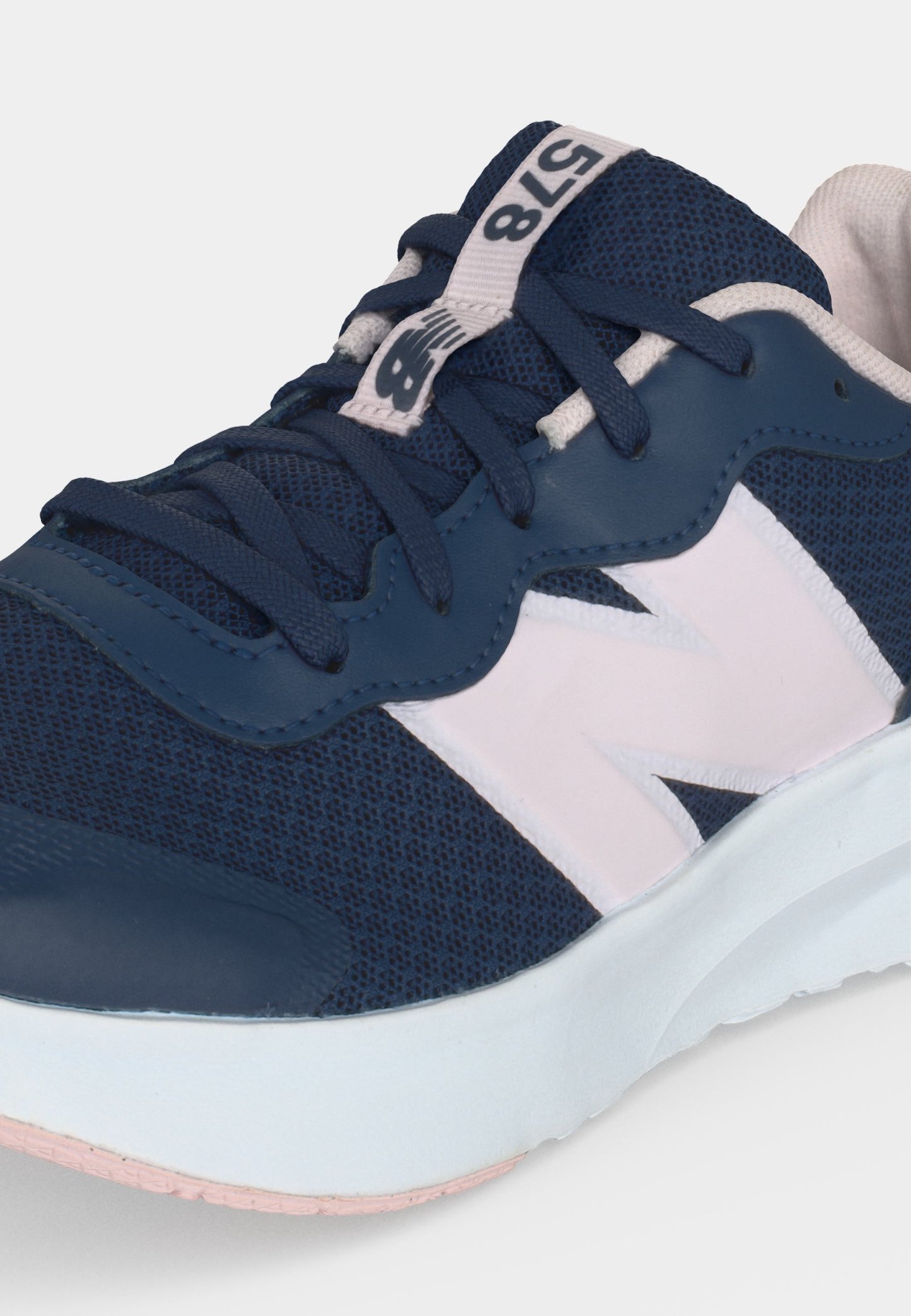 Zapatilla New Balance azul marino y blanca con parte superior de malla, cordones azul oscuro y entresuela blanca, mostrando el logo lateral y la etiqueta en la lengüeta.