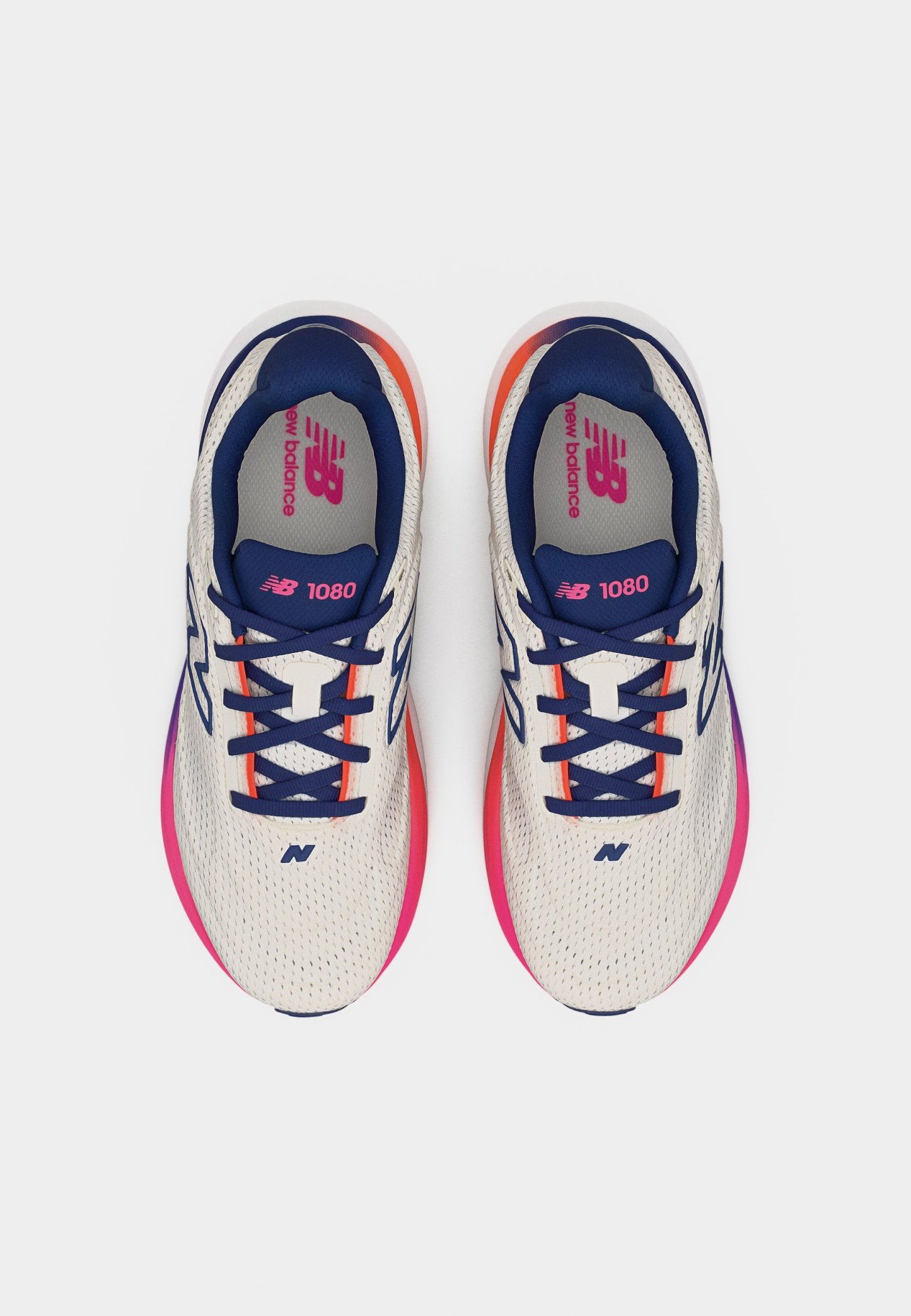 Par de zapatillas New Balance 1080 blancas con cordones azul marino y suelas con degradado rosa-naranja, vistas desde arriba sobre un fondo blanco.