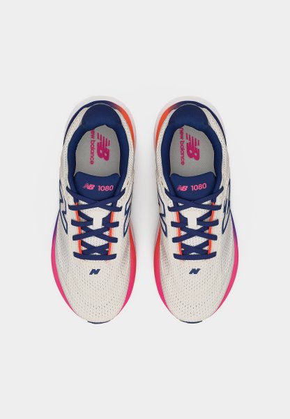 Par de zapatillas New Balance 1080 blancas con cordones azul marino y suelas con degradado rosa-naranja, vistas desde arriba sobre un fondo blanco.