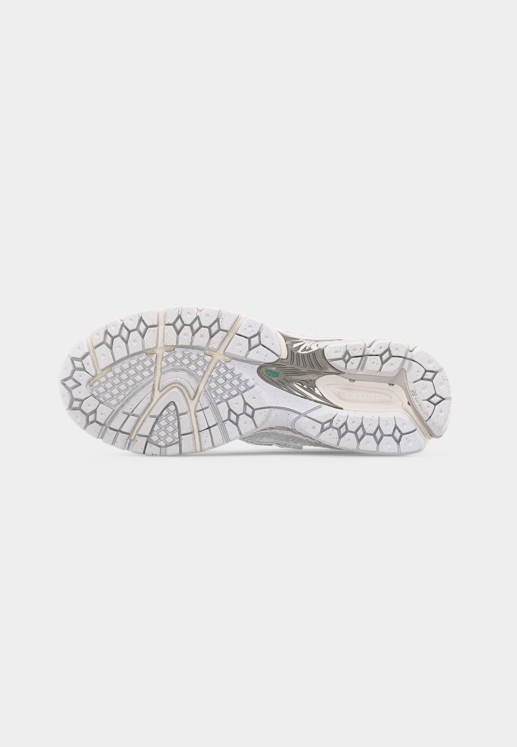 Suela de un zapato deportivo blanco y gris con un patrón de tracción de panal y cuadrícula sobre un fondo blanco liso.