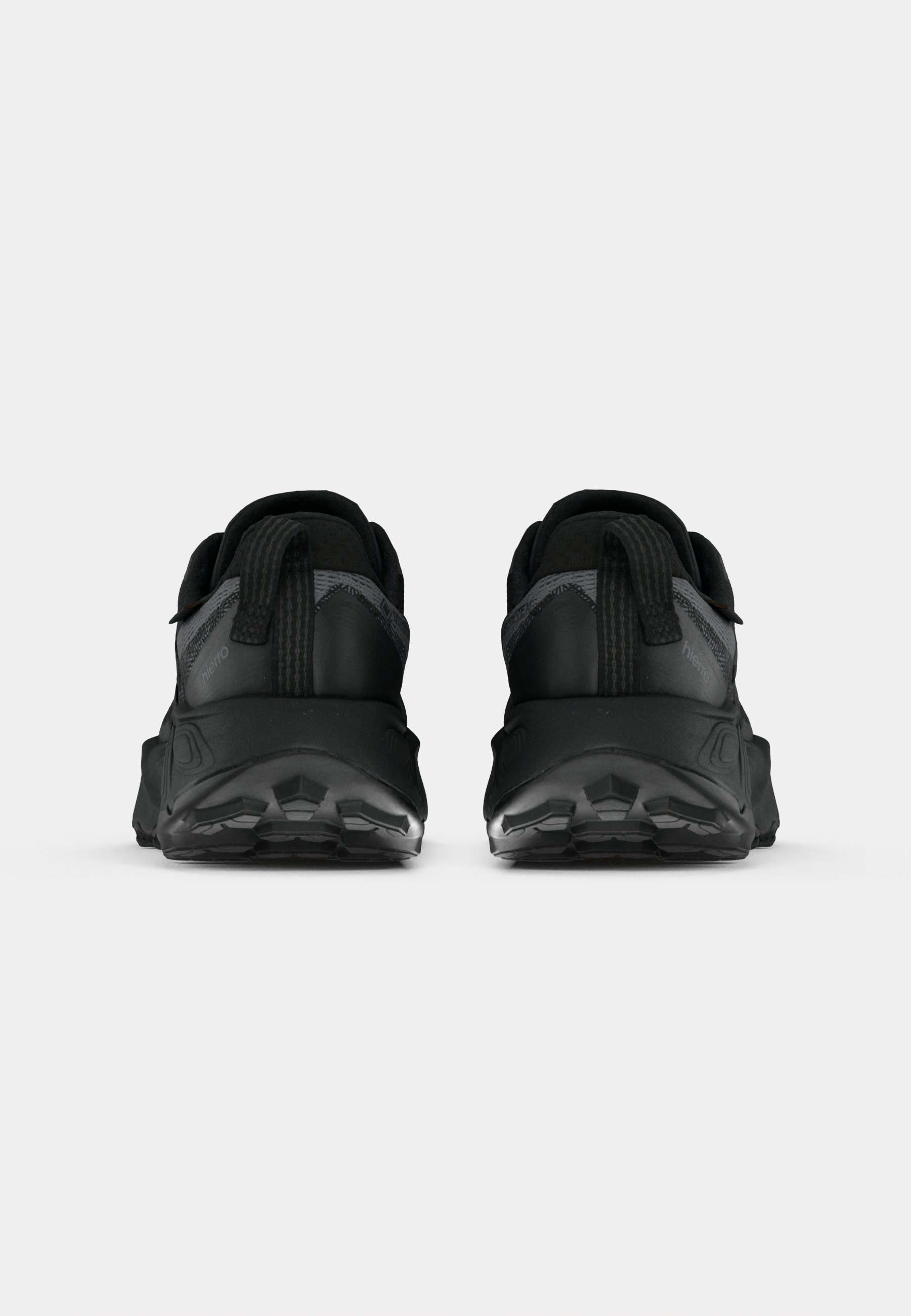 Zapatillas deportivas negras con parte superior texturizada, talón reforzado y suela negra gruesa con patrones de tracción. Dos tiradores traseros para ponerlas y quitarlas fácilmente.