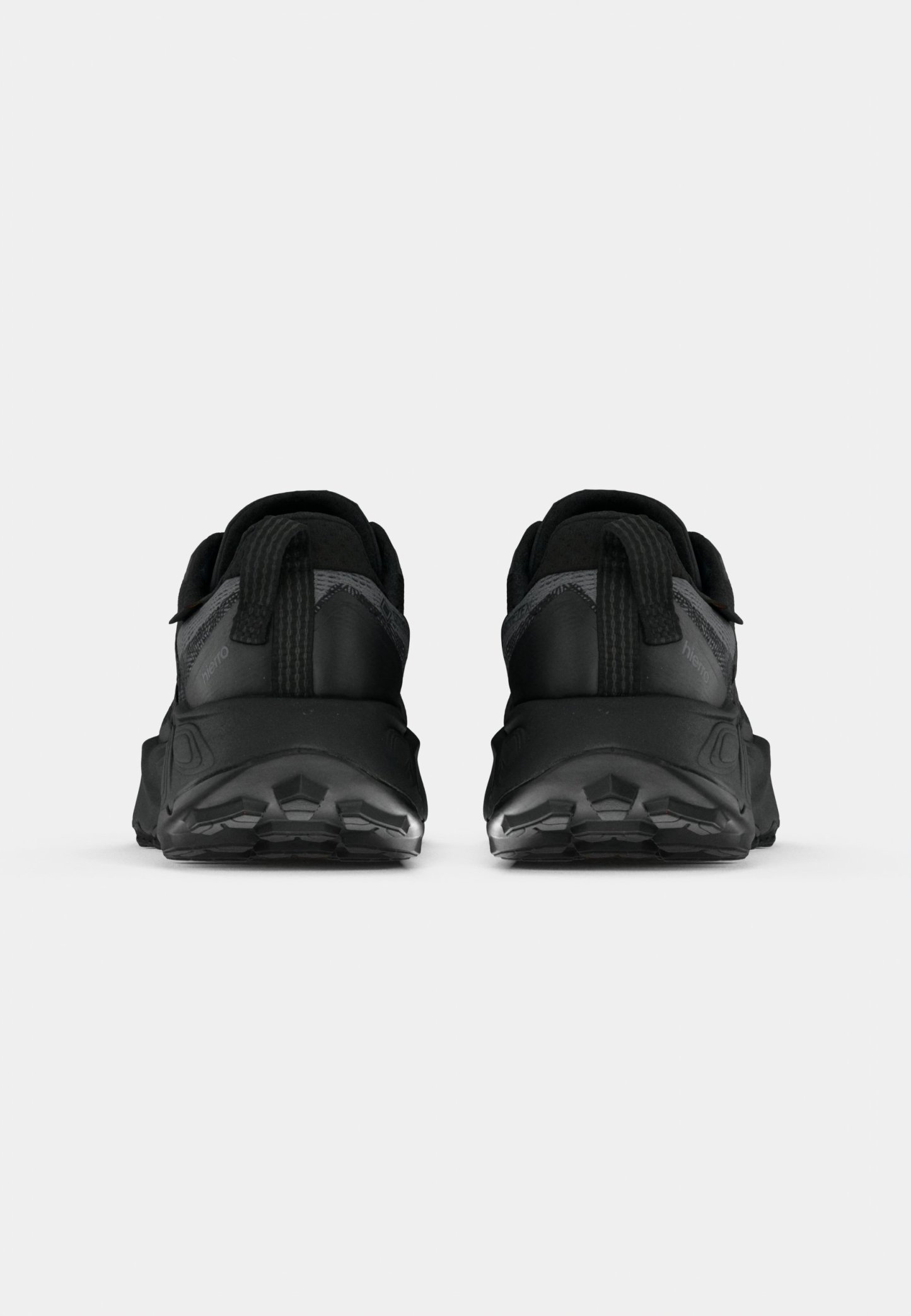 Zapatillas deportivas negras con parte superior texturizada, talón reforzado y suela negra gruesa con patrones de tracción. Dos tiradores traseros para ponerlas y quitarlas fácilmente.