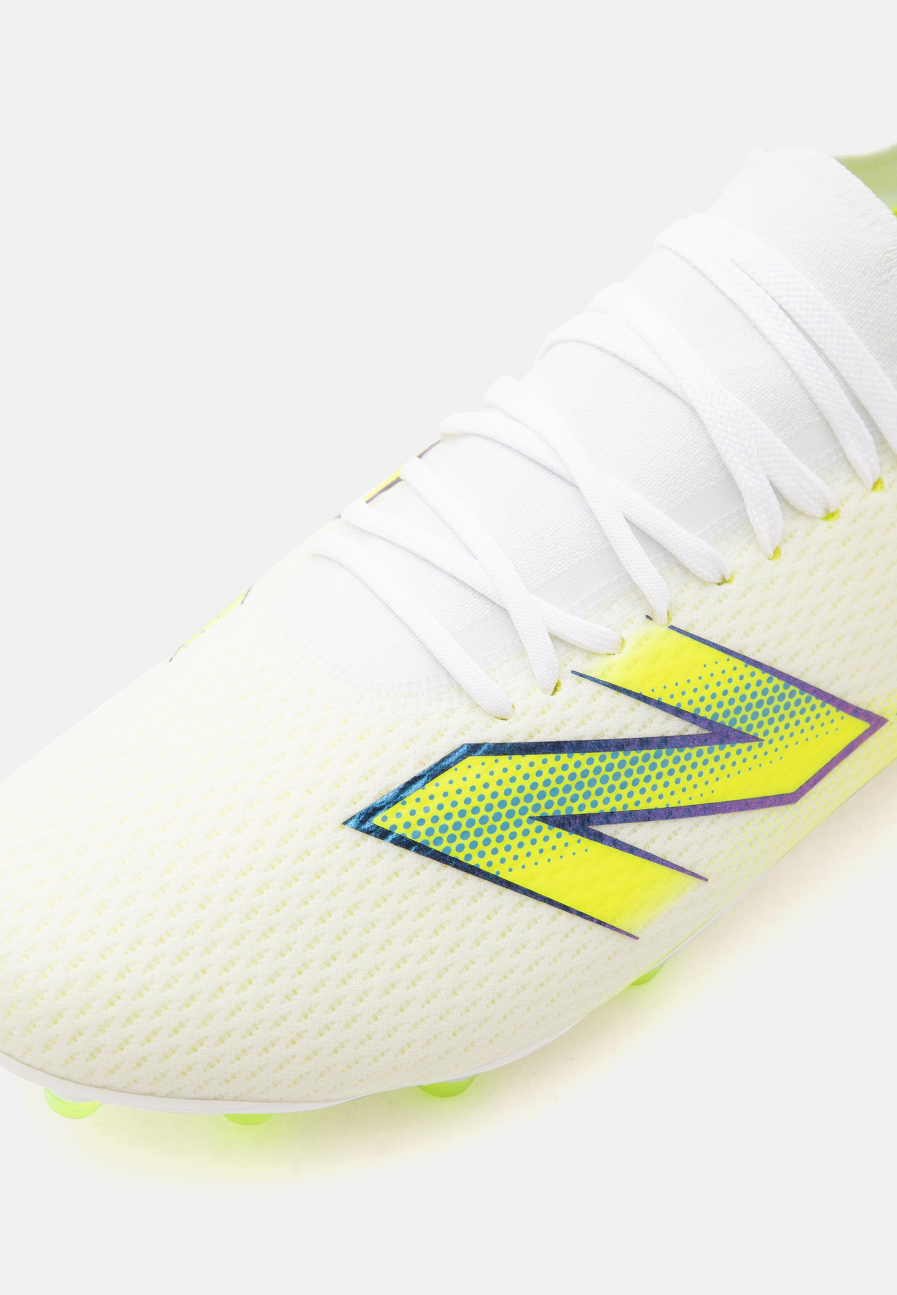 Primer plano de una bota de fútbol blanca con cordones blancos y un logotipo estilizado "N" amarillo y azul en el lateral.