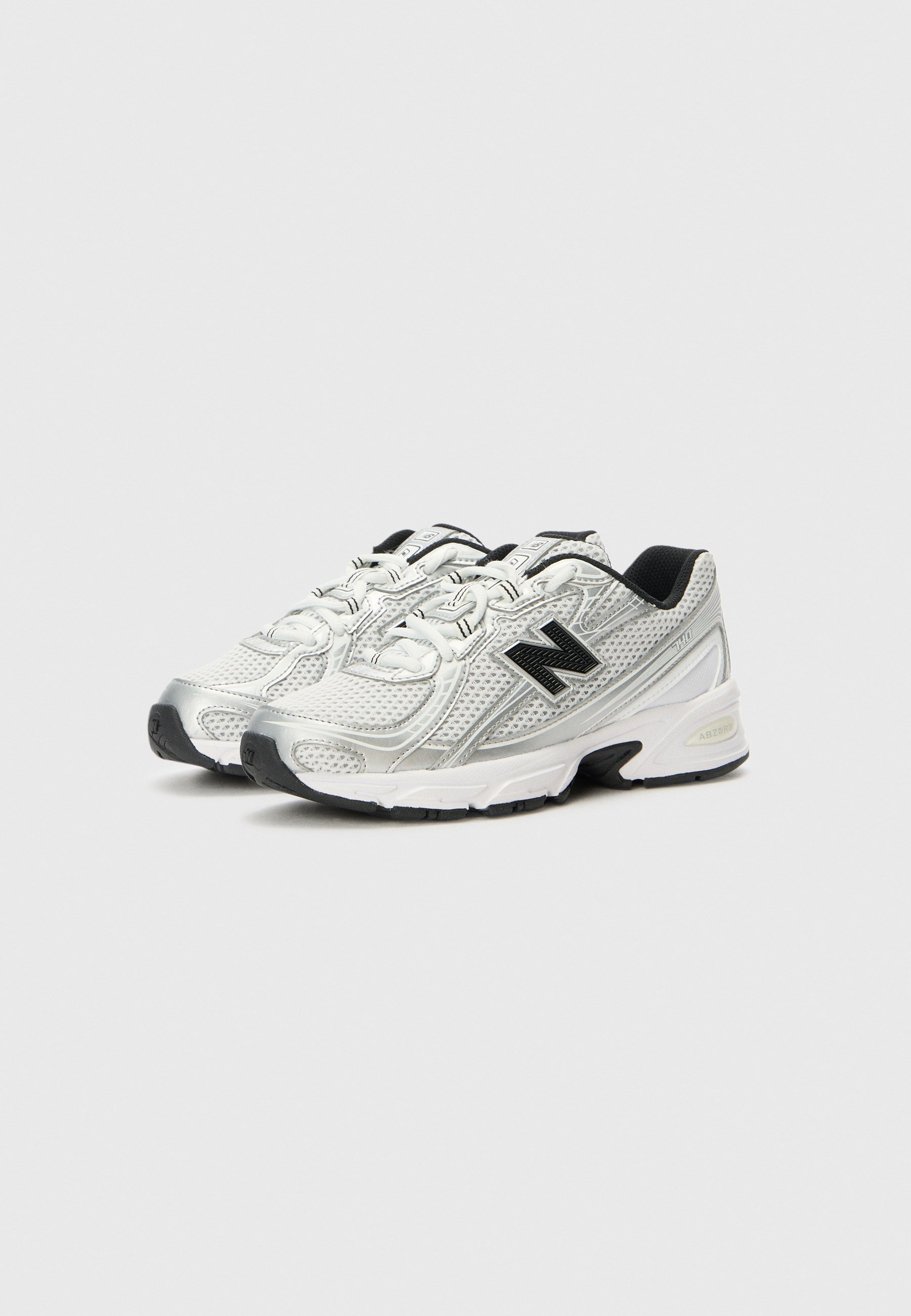 Par de zapatillas de correr New Balance blancas y plateadas con logo negro y suelas negras sobre un fondo claro.