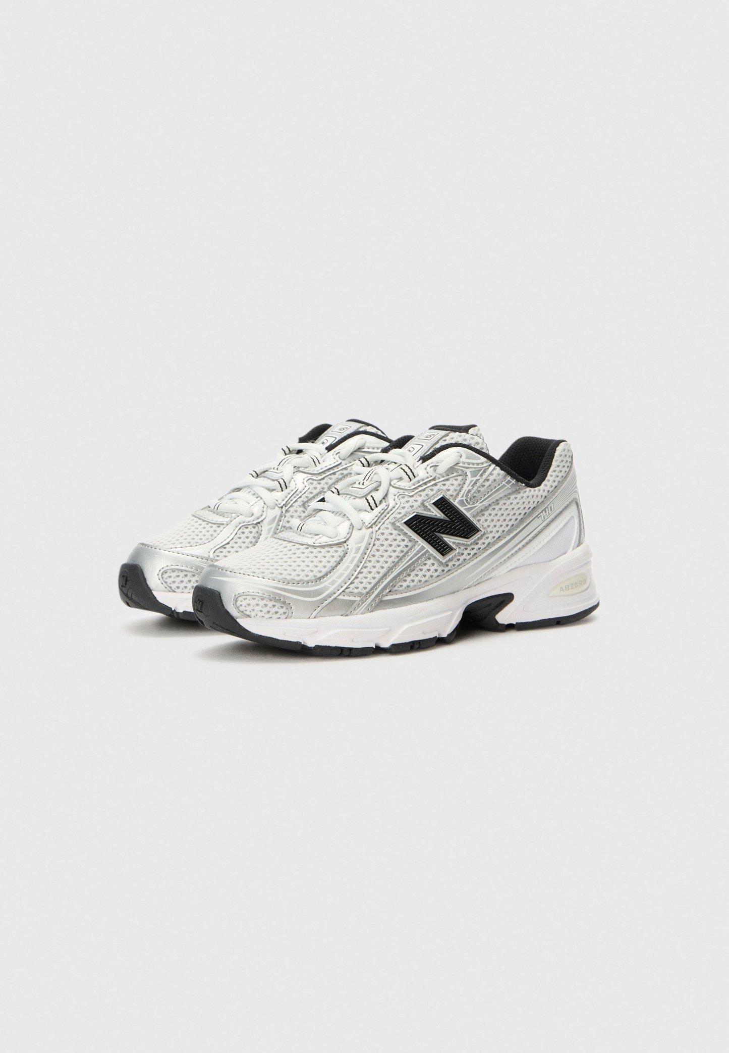 Par de zapatillas de correr New Balance blancas y plateadas con logo negro y suelas negras sobre un fondo claro.