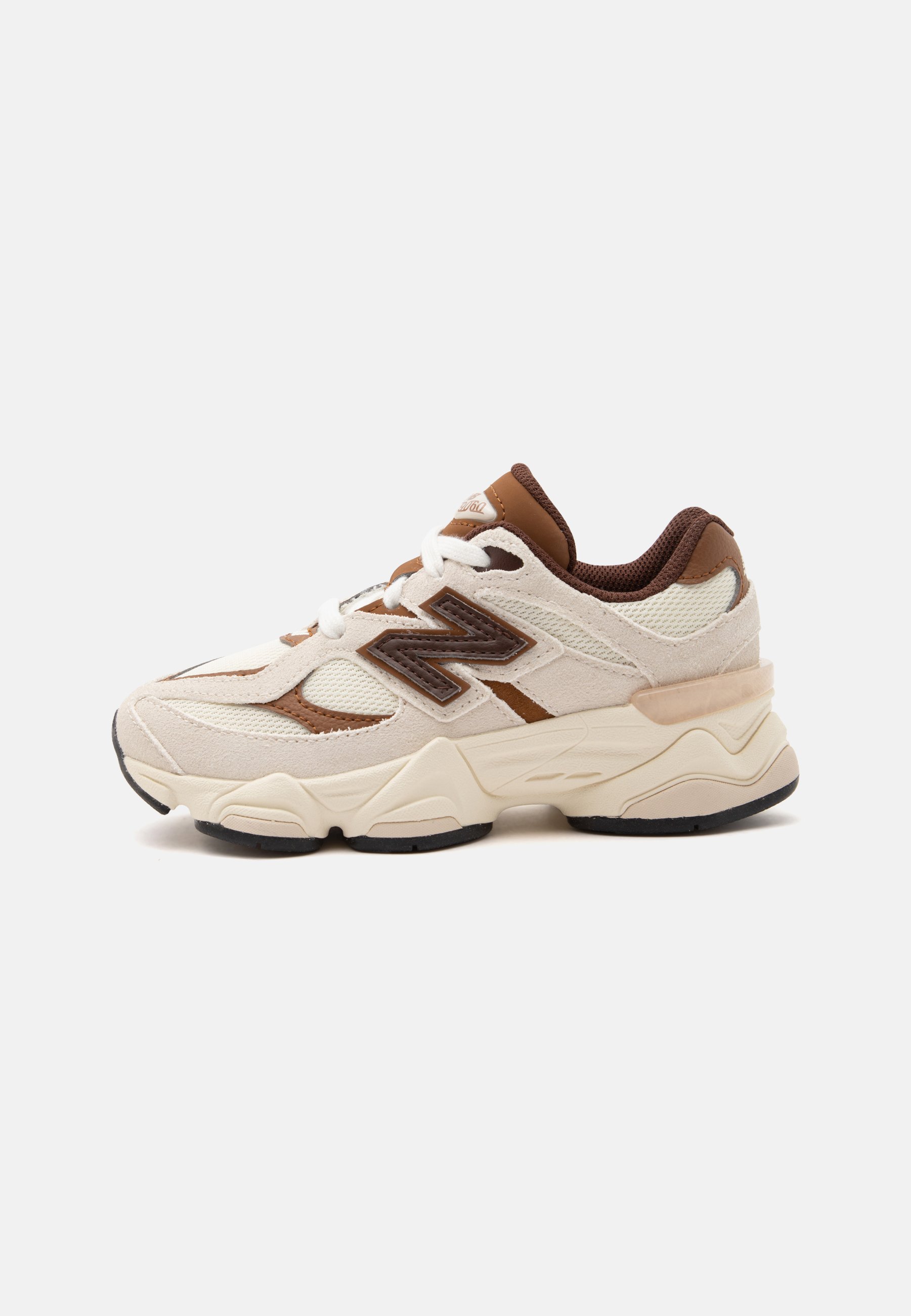 Zapatilla New Balance beige y marrón con parte superior de malla y ante, suela gruesa acolchada y cordones blancos sobre un fondo liso.